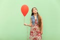 The beautiful blonde teenager dreaming, with red ballons on a green background.