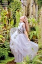 A beautiful blonde twirls in an elegant tulle dress in a botanical garden