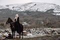 Beautiful blonde Viking in a black cape on horseback Royalty Free Stock Photo