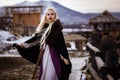 Beautiful blonde Viking dressed in a black cloak against the backdrop of the castle Royalty Free Stock Photo