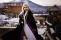 Beautiful blonde Viking dressed in a black cloak against the backdrop of the castle Royalty Free Stock Photo