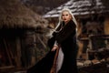 Beautiful blonde Viking dressed in a black cloak against the backdrop of the castle Royalty Free Stock Photo