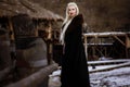 Beautiful blonde Viking dressed in a black cloak against the backdrop of the castle Royalty Free Stock Photo