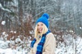 Beautiful blonde in a warm blue hat. Winter style for young women. Beautiful attractive female smile. Winter forest and