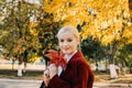 Beautiful blonde Woman with Autumn Leaves on Fall Nature Background. Alone brooding woman in red coat holding autumn leafs in the