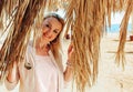 Beautiful blonde woman on a background of dry leaves and palm branches on the beach