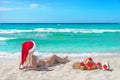 Beautiful blonde woman in bikini, red christmas hat and gift box Royalty Free Stock Photo