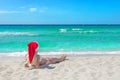 Beautiful blonde woman in bikini and red christmas hat on sea be Royalty Free Stock Photo