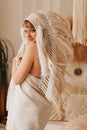 a beautiful blonde woman in a blanket in an Indian headdress of white feathers Royalty Free Stock Photo