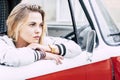 Beautiful blonde woman with blue eyes looking at the orizont - adult with great red and white van - lifestyle concept