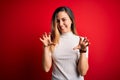 Beautiful blonde woman with blue eyes wearing casual white t-shirt over red background smiling funny doing claw gesture as cat, Royalty Free Stock Photo