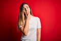 Beautiful blonde woman with blue eyes wearing casual white t-shirt over red background Thinking worried about a question, Royalty Free Stock Photo