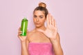 Beautiful blonde woman with blue eyes wearing towel shower after bath holding aloe vera gel with open hand doing stop sign with Royalty Free Stock Photo