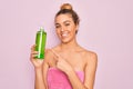 Beautiful blonde woman with blue eyes wearing towel shower after bath holding aloe vera gel very happy pointing with hand and Royalty Free Stock Photo