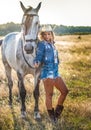 Beautiful blonde woman with curly hair with white hat and horse. Portrait of a girl with denim and her horse Royalty Free Stock Photo