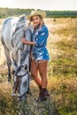 Beautiful blonde woman with curly hair with white hat and horse. Portrait of a girl with denim and her horse Royalty Free Stock Photo