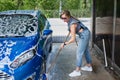 beautiful blonde woman in denim overalls washes the car Royalty Free Stock Photo