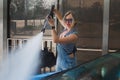beautiful blonde woman in denim overalls washes the car Royalty Free Stock Photo