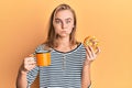 Beautiful blonde woman eating doughnut and drinking coffee puffing cheeks with funny face Royalty Free Stock Photo