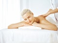 Beautiful blonde woman enjoying back massage with closed eyes. Spa salon concept Royalty Free Stock Photo