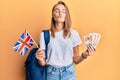 Beautiful blonde woman exchange student holding uk flag and pounds looking at the camera blowing a kiss being lovely and sexy