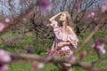 Beautiful blonde woman in a flowered Peach Garden in spring with pink flowers Royalty Free Stock Photo