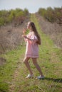 Beautiful blonde woman in pink dress walks through the flowering garden Royalty Free Stock Photo