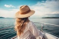 blonde woman with hat sits on a yacht and enjoys the summer holiday over the tropical ocean, AI Generated Royalty Free Stock Photo