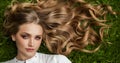 Beautiful blonde woman with long curly hair and healthy skin on green grass outdoor, top view Royalty Free Stock Photo