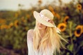 Beautiful blonde woman with long hair and sunhat in a rural sunflowers field Royalty Free Stock Photo