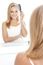 beautiful blonde woman with long hair tidy up her hair using hair comb Royalty Free Stock Photo