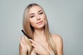 Beautiful blonde woman with long healthy straight hair combing hair. Haircare concept. Girl combs hair