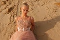 Beautiful blonde woman lying on sand posing in embroidery dress on desert. Summer photo. Sunny day Royalty Free Stock Photo