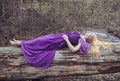 Beautiful blonde woman lying on the tree by the river