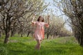 Beautiful blonde woman in pink dress on the road in the flowering garden in spring Royalty Free Stock Photo