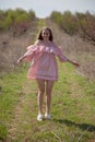 Beautiful blonde woman in pink dress on the road in the garden in the spring
