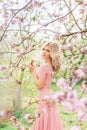 Beautiful blonde woman in a pink long dress in a spring blooming garden Royalty Free Stock Photo