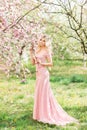 Beautiful blonde woman in a pink long dress in a spring blooming garden Royalty Free Stock Photo