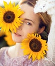 Beautiful blonde woman portrait close up, with sunflowers in a rural field outdoors Royalty Free Stock Photo