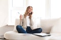 Beautiful blonde woman posing sitting indoors at home using laptop computer talking by mobile phone Royalty Free Stock Photo