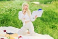 A beautiful blonde woman reading a book in a meadow and being inspired. Picnic