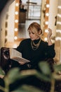 Beautiful blonde woman reads an interesting book in a cozy atmosphere at home. Soft selective focus, defocus, art noise Royalty Free Stock Photo