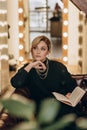 Beautiful blonde woman reads an interesting book in a cozy atmosphere at home. Soft selective focus, defocus, art noise Royalty Free Stock Photo