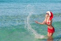 Beautiful blonde woman in red christmas hat on sea beach Royalty Free Stock Photo