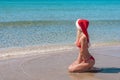 Beautiful blonde woman in red christmas hat on sea beach. Royalty Free Stock Photo