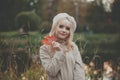 Beautiful blonde woman with red fall maple leaf on autumn background Royalty Free Stock Photo