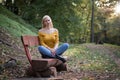 Beautiful blonde woman sitting on a wooden bench in the forest Royalty Free Stock Photo