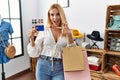 Beautiful blonde woman at retail shop holding credit card smiling happy pointing with hand and finger