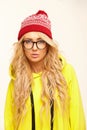 Beautiful blonde woman with round spectacles on white isolated background, wears red cap and yellow sweatshirt.