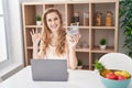 Beautiful blonde woman shopping online with laptop doing ok sign with fingers, smiling friendly gesturing excellent symbol Royalty Free Stock Photo